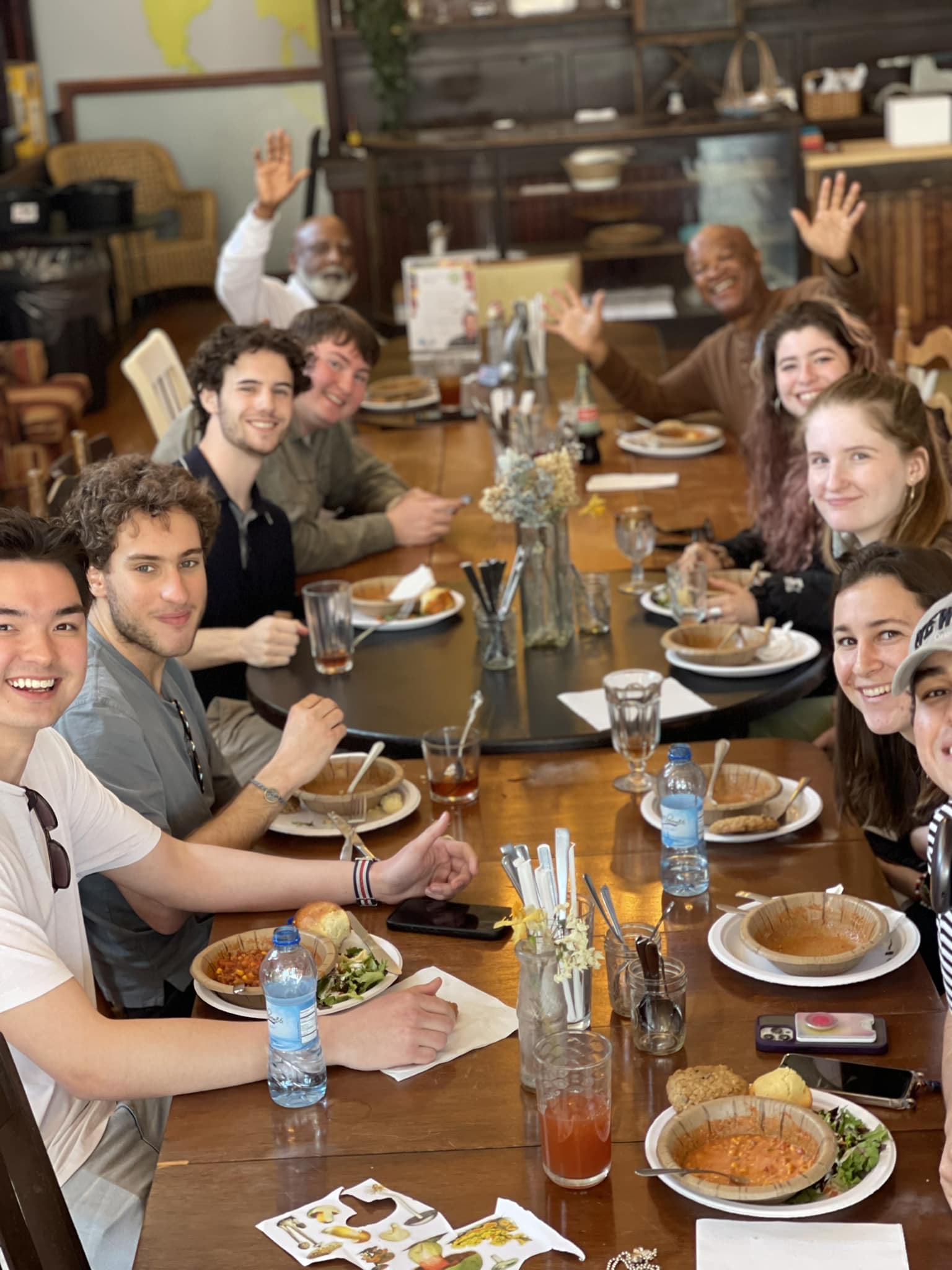 People smiling at the camera while eating chili sitting family style at a restaurant