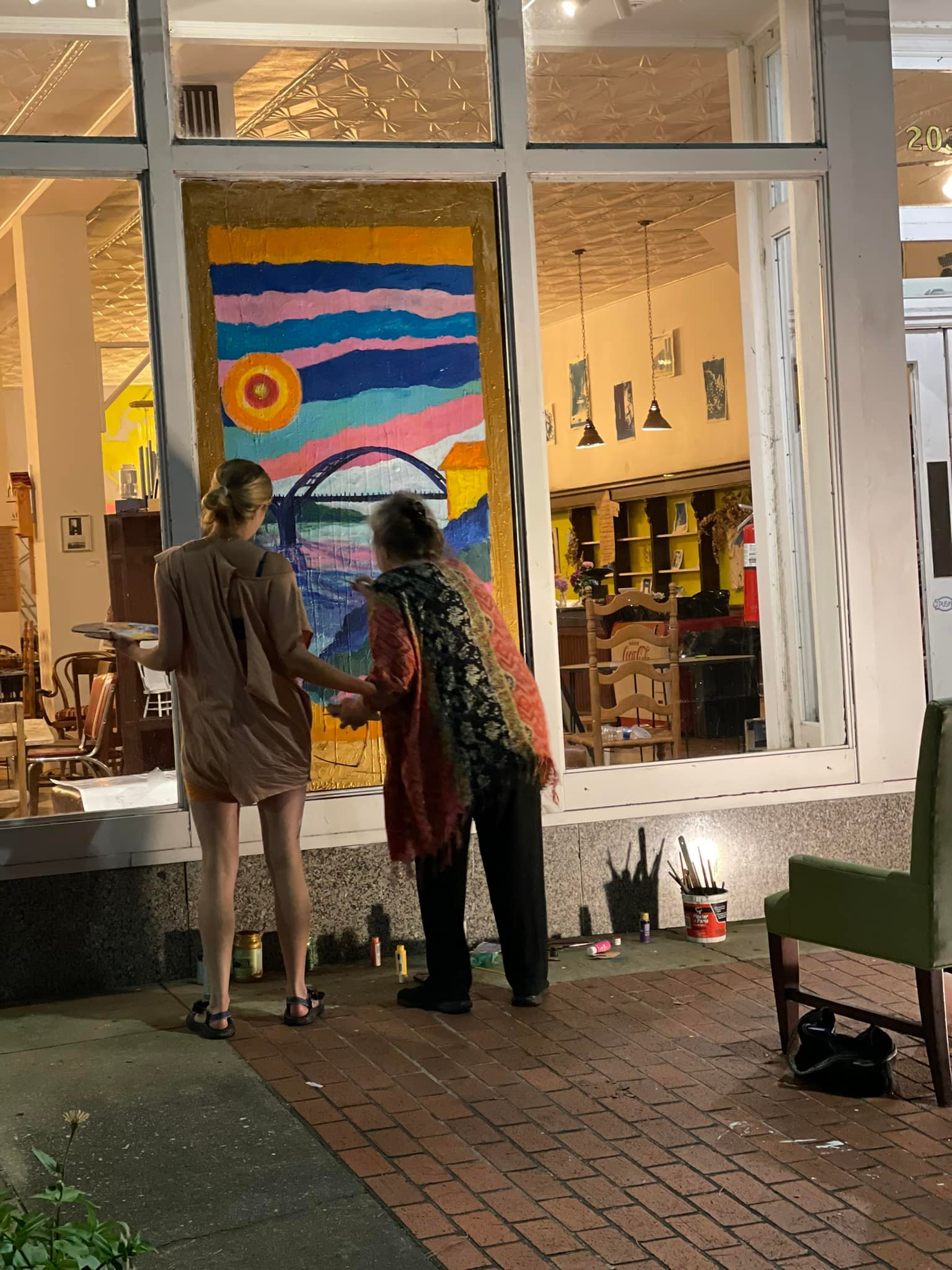 Granddaughter holds grandmother steady as she paints a window